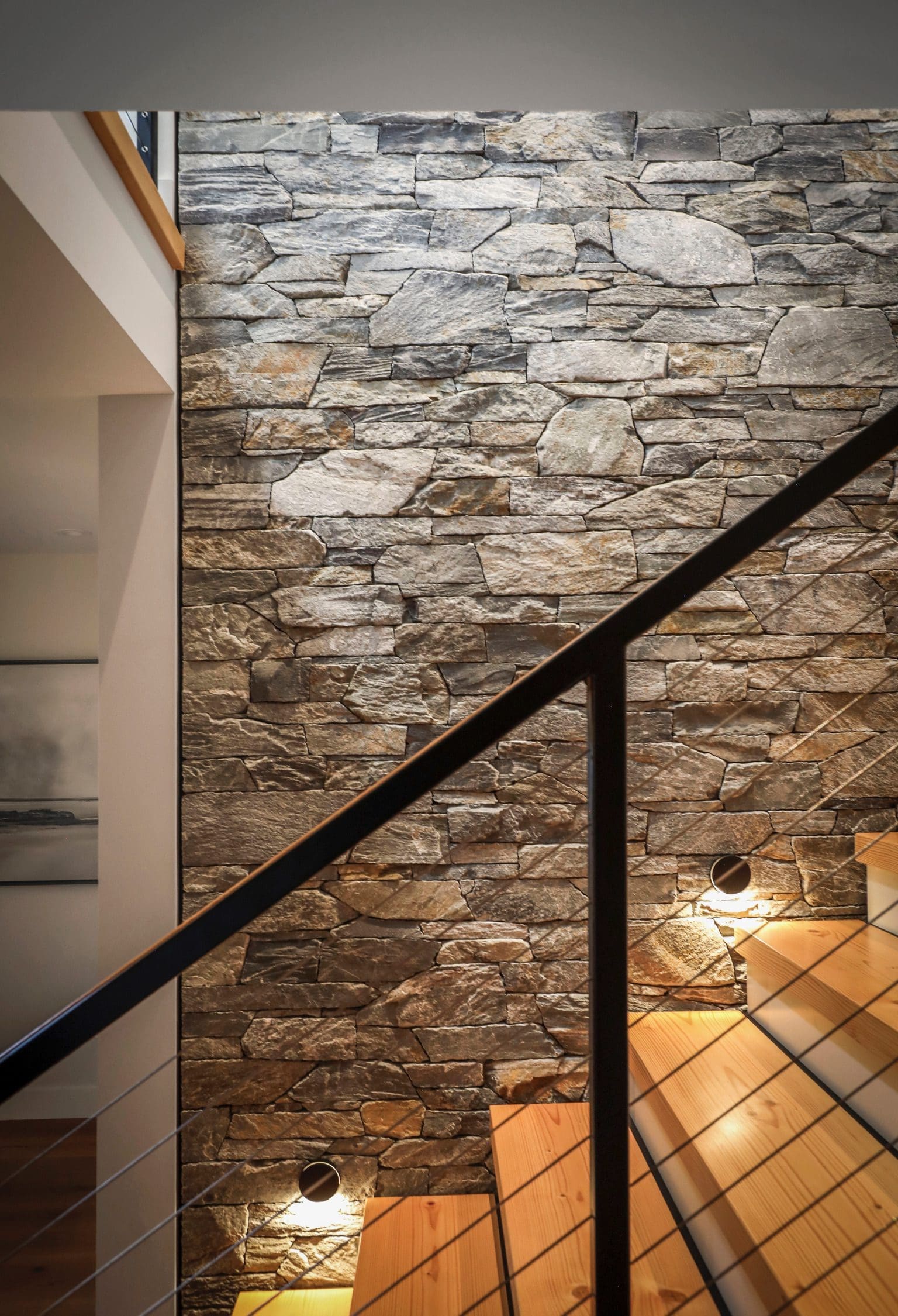 Interior stone feature wall along staircase, custom masonry installation by Central Masonry in the Comox Valley