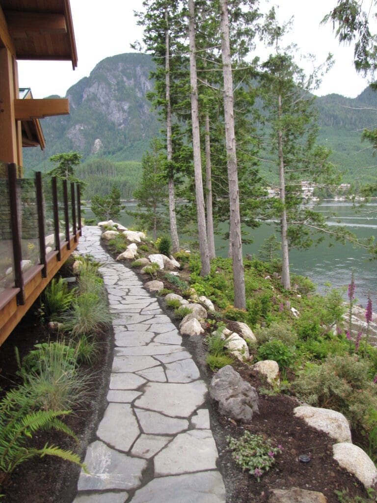 Hand-laid flagstone pathway winding through lush West Coast landscaping on a waterfront property in BC’s Discovery Islands, built by Central Masonry